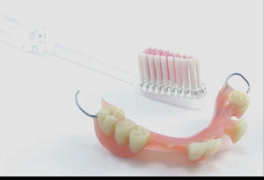 A denture beside a toothbrush, showing the care dentures require.